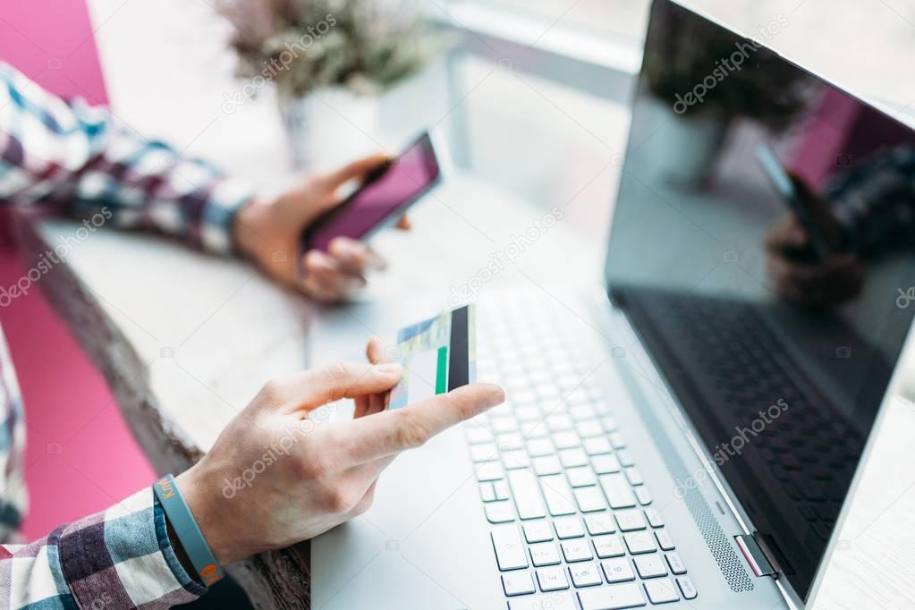 Young man with credit card payments through the Internet, finding the item on the Internet