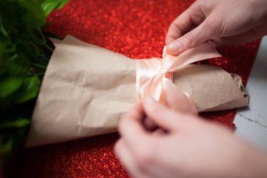Sevgililer günü, çiçekçi kadın paketleri bir buket çiçek gül ahşap masa, reklam için uygun bir yay ile bir kağıt ambalajı içinde,