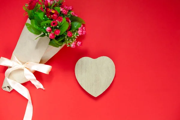 Regalo de San Valentín para la segunda mitad, un ramo de flores, una foto romántica, un corazón de madera sobre un fondo rojo, fondo adecuado para la publicidad, inserte texto — Foto de Stock