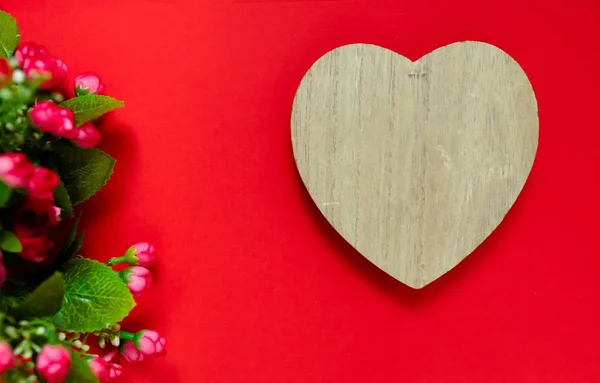 Regalo de San Valentín para la segunda mitad, un ramo de flores, una foto romántica, un corazón de madera sobre un fondo rojo, fondo adecuado para la publicidad, inserte texto — Foto de Stock