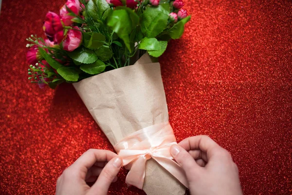 Día de San Valentín, florista mujer paquetes de un ramo de flores de rosas en una envoltura de papel con un arco en la mesa de madera, adecuado para la publicidad , — Foto de Stock