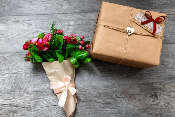 Becsomagolt ajándékot a fa szürke háttér, Valentin-nap romantikus képek, romantikus virágcsokor szívvel és ajándékok, alkalmas a reklám — Stock Fotó