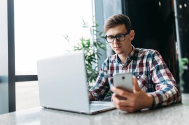 Bir adam bir kafede oturuyor ve dizüstü bilgisayar, iş, aramaya çalışan öğrenci ödev, bir adam bir gömlek ve gözlük yazıyor