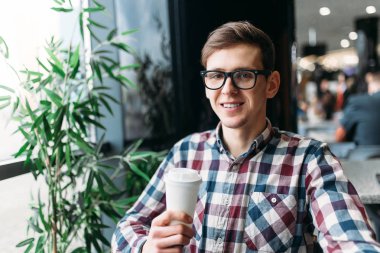 Bir beyaz kağıt bardak, yakışıklı bir adam, hücresel bir gömlek içinde tutan bir adam