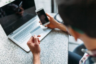 Bir adam ile bir dizüstü bilgisayar, yapmak alışveriş online store üzerinden, kredi kartı ile ödeme, plastik kart bir kafede oturuyor