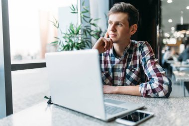 Bir adam bir kafede oturuyor ve dizüstü bilgisayar, iş, aramaya çalışan öğrenci ödev, bir adam bir gömlek ve gözlük yazıyor