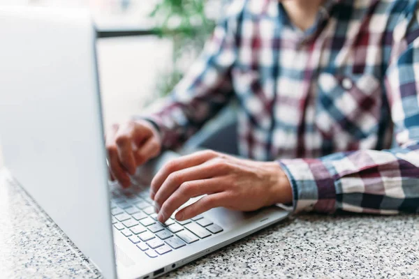 Primer plano del brazo masculino, escribiendo en el ordenador portátil, búsqueda de empleo, trabajo en línea, en un café con un ordenador portátil — Foto de Stock