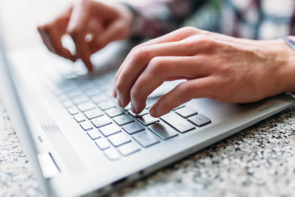 Primer plano del brazo masculino, escribiendo en el ordenador portátil, búsqueda de empleo, trabajo en línea, en un café con un ordenador portátil — Foto de Stock