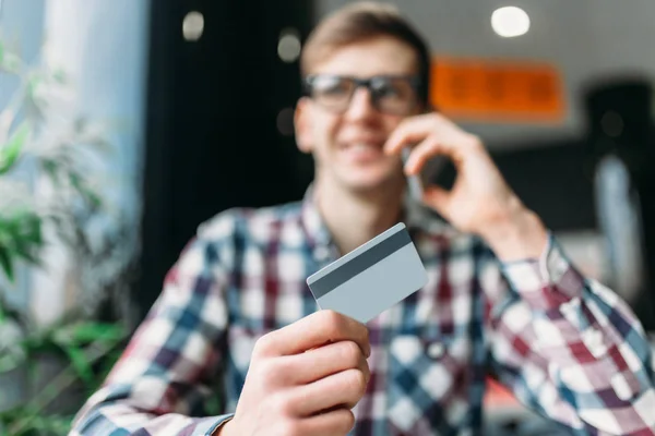 Un uomo si siede in un caffè con un computer portatile, fare acquisti tramite il negozio online, il pagamento con carta di credito, una carta di plastica — Foto Stock