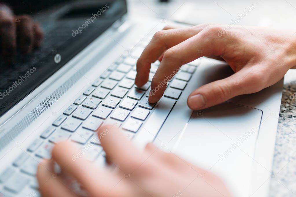 Closeup of male arm, typing on laptop, job search, job online, in a cafe with a laptop