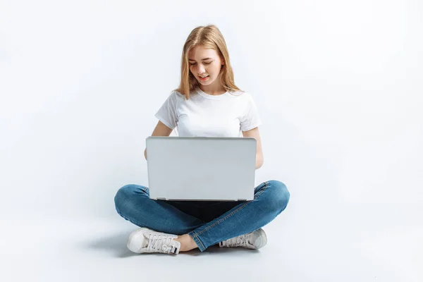Hermosa chica sentada y escribiendo en el ordenador portátil, compras, en el estudio, fondo aislado —  Fotos de Stock