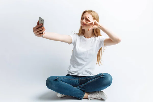 Het meisje in de Studio doen een selfie, witte achtergrond, geïsoleerd — Stockfoto