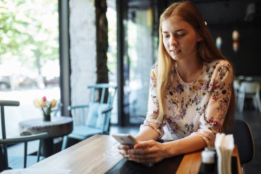 Kafede boş zamanlarında, kahvede yorgunluk sohbet bir cep telefonu ile sevimli bir gülümseme ile çekici kadın tek başına oturmak telefonda konuşurken genç çekici kız