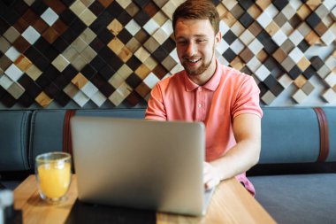 Çalışma, alışveriş online, yenilikçi bir dizüstü bilgisayar ile bir kafede oturan bir genç adam