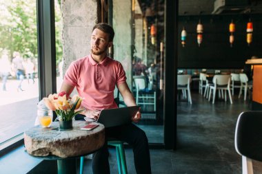 Çalışma, alışveriş online, yenilikçi bir dizüstü bilgisayar ile bir kafede oturan bir genç adam