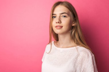 Pembe arka plan l üzerinde duran güzel bir genç kız portresi