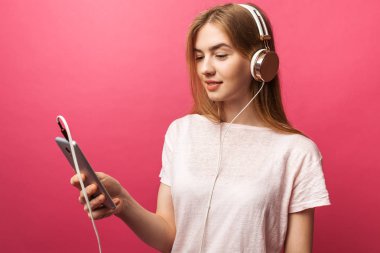 Boş ekran cep telefonu reklam iş pembe, izole gösterilen kulaklık dinleme müzik neşeli mutlu kız portresi