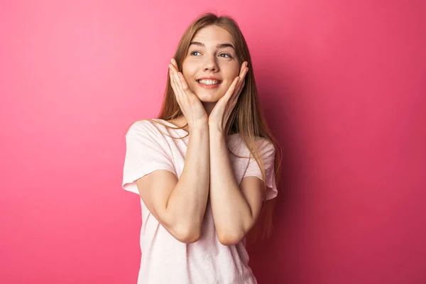 Ritratto di una bella ragazza in piedi su sfondo rosa guardando la macchina fotografica, sorride ed è felice — Foto Stock