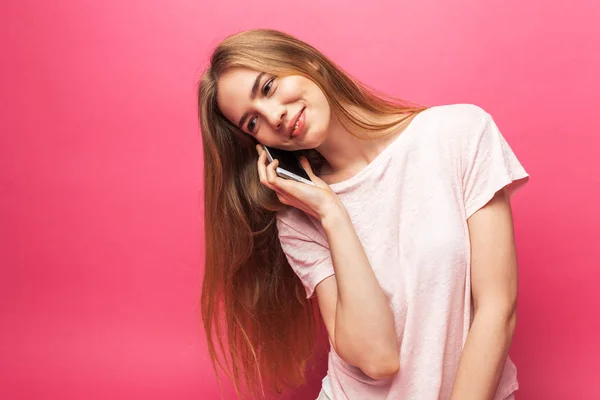 Портрет веселої красивої дівчини, що розмовляє по телефону, виглядає досить смішно, ізольовано на рожевому фоні, реклама — стокове фото