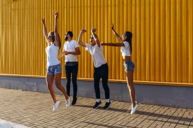 Mutlu genç arkadaşlar, erkekler ve kadınlar şehirde eğlenip zıplıyorlar.