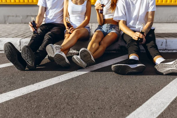 Un grup de tineri prieteni stau în oraș așezați pe asfalt la peretele galben — Fotografie, imagine de stoc