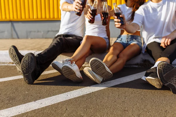 Een groep jonge vrienden hangt rond in de stad zittend op het asfalt bij de gele muur — Stockfoto