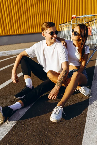 A young guy and a girl pose sitting on the asphalt, in the city — Stockfoto