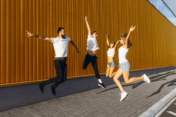 Ευτυχισμένοι νέοι φίλοι, άνδρες και γυναίκες διασκεδάζουν και πηδούν στην πόλη — Φωτογραφία Αρχείου