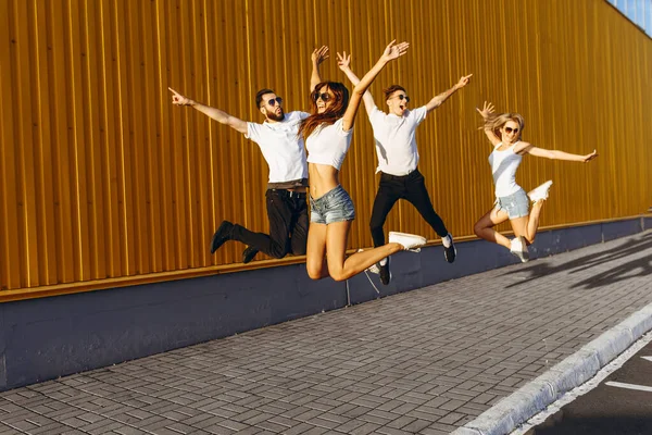 Giovani amici felici, uomini e donne si divertono e saltano in città — Foto Stock