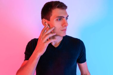 Çekici bir adam arka planda neon ışıkla duruyor.