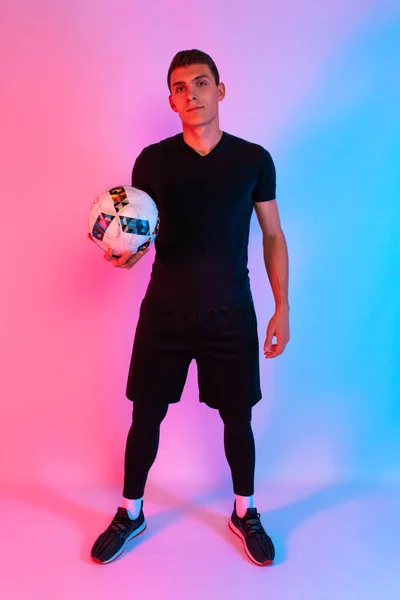 A football player in a black sports uniform holds the ball in hi — 스톡 사진