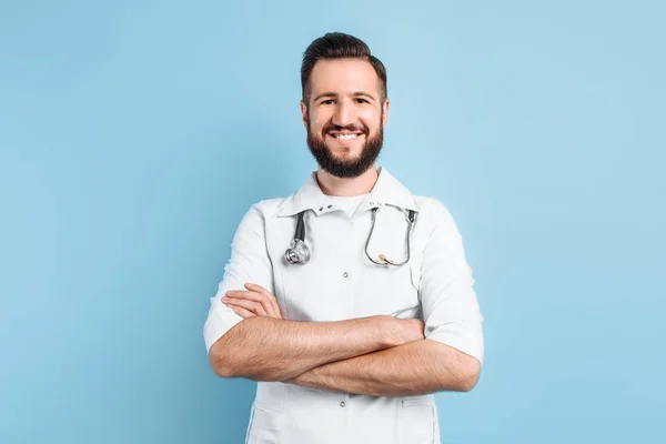 Een positieve mannelijke dokter kijkt naar de camera met gekruiste armen — Stockfoto