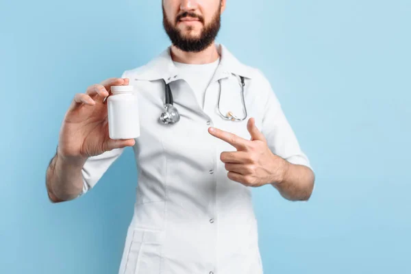 Médecin avec un pot de médicaments sur fond bleu — Photo