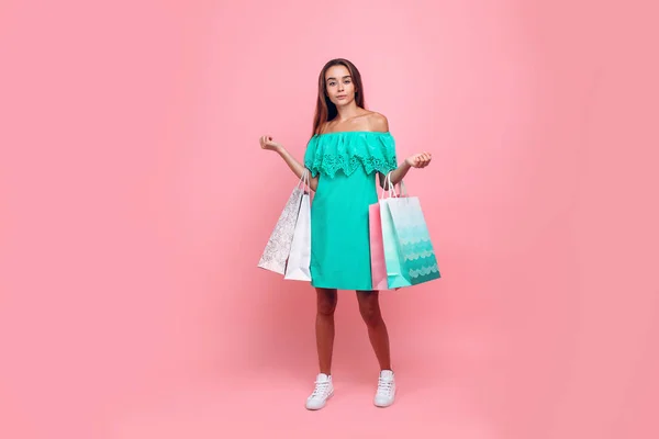 Porträt einer stilvoll lächelnden schönen Frau in einem schulterfreien Kleid mit Taschen auf isoliertem rosa Hintergrund — Stockfoto