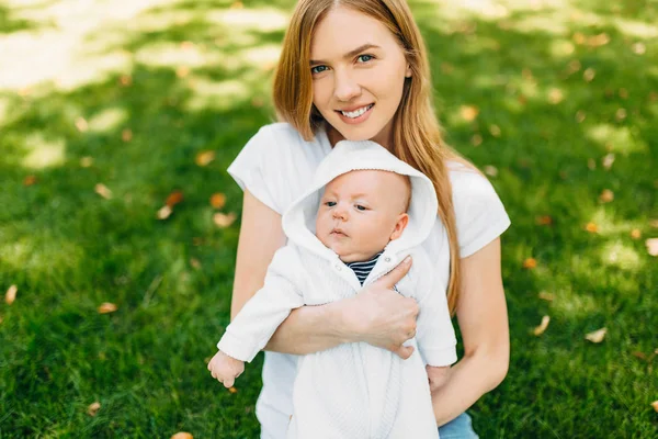 Familia feliz al aire libre, madre con un bebé en sus brazos — Foto de Stock