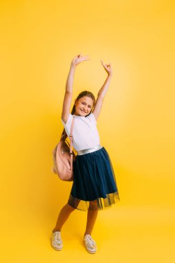Charming little student on a yellow background. The pupil of a s