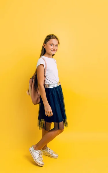 Retrato de una colegiala sonriente con una mochila en un yel —  Fotos de Stock