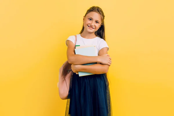 Een tiener met een rugzak en boeken. Stijlvol mooi schoolmeisje poseren op een gele achtergrond — Stockfoto