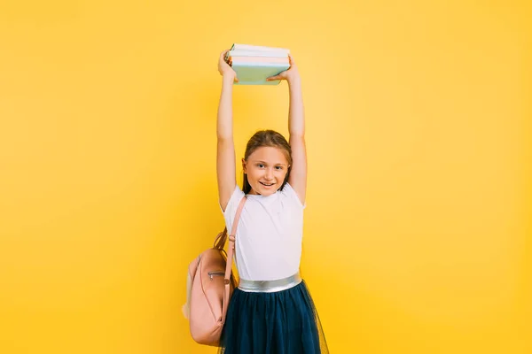 A teenager with a backpack and books. Stylish beautiful schoolgirl posing on a yellow background — Stock Photo, Image