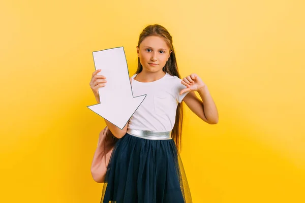 Portrait of a shocked teenage schoolgirl girl, with an arrow pointing to the copy space — Stock Photo, Image