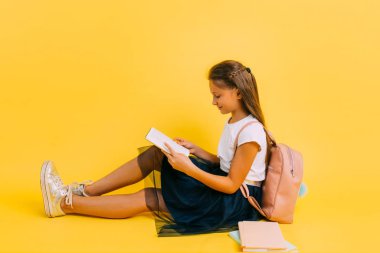 Smart teenage girl in school clothes doing homework reading a book