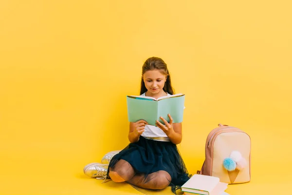 Smart teenage girl in school clothes doing homework reading a book — 图库照片