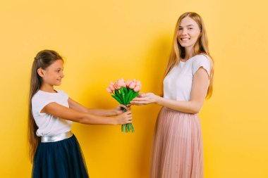 Anne ve kızı, küçük bir kız annesine bir buket çiçek verir.