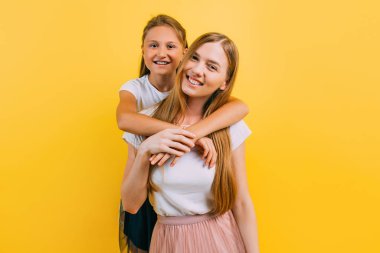 Çekici kızıyla birlikte izole edilmiş sarı bir arka planda güzel bir genç kadının tam boy fotoğrafı.