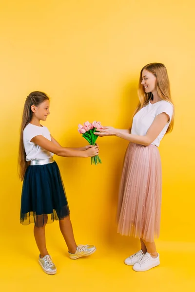 Anne ve kızı, küçük bir kız annesine bir buket çiçek verir. — Stok fotoğraf