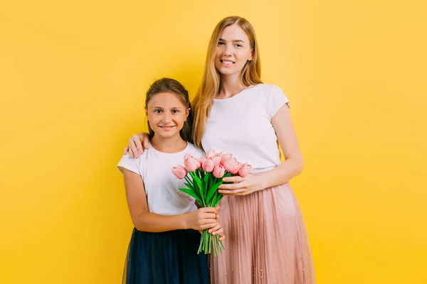 Madre e hija, una niña le da a su madre un ramo de flores —  Fotos de Stock