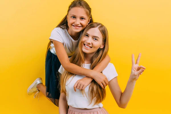 Foto de larga duración de una hermosa joven con su pequeña hija encantadora, sobre un fondo amarillo aislado —  Fotos de Stock