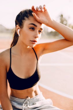 Sabahları inanılmaz güzel güçlü atletik kadın görüntü, kablosuz kulaklık ile müzik dinleyen yorgun sporcu