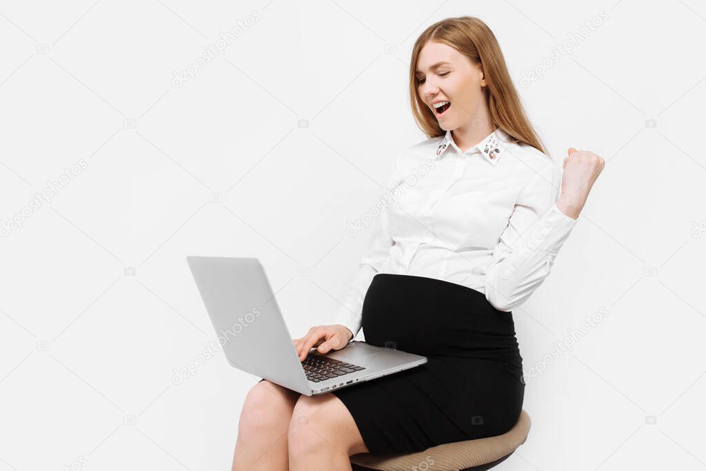 Image of a young pregnant businesswoman in glasses, a girl working with a laptop, depicting a gesture of victory and success, sitting on a chair, on a white background