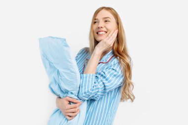 Pijamalı güzel bir kızın portresi. Yastık tutuyor. Beyaz arka planda tatlı rüyalar görmeye gitmeden önce hayalperest.